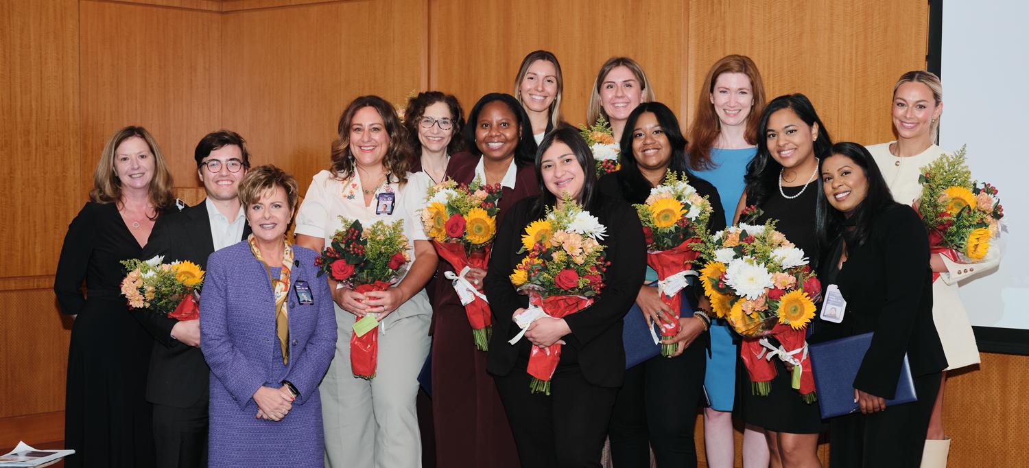 Participants in the symposium smiling, with many holding bouquets of flowers