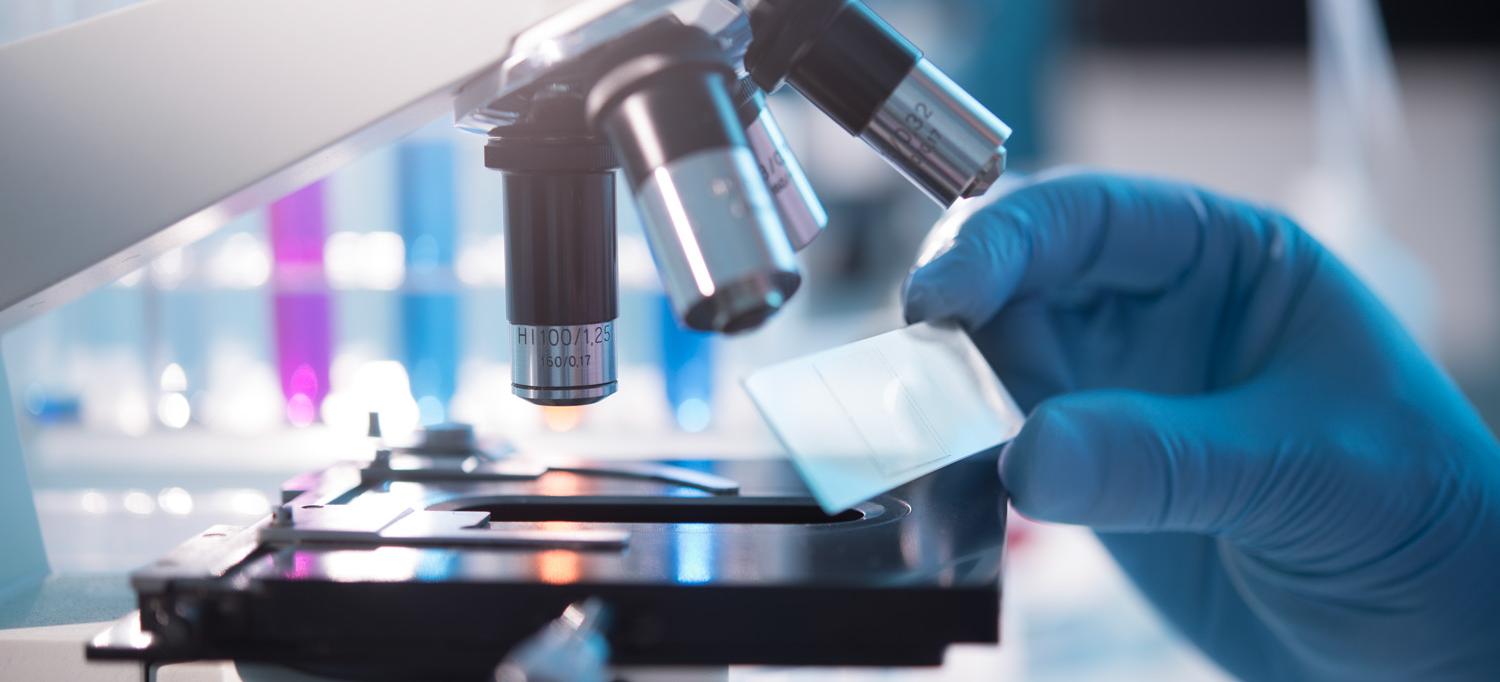 A scientist placing a slide under a microscope