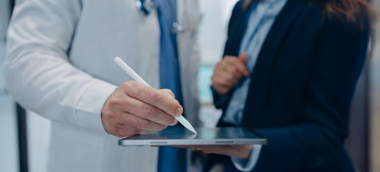 Close-up of provider in white coat signing a contract