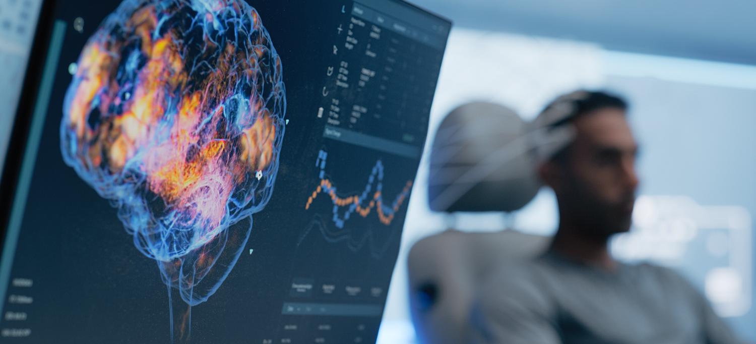 Brain waves on a screen and a man in a chair. 