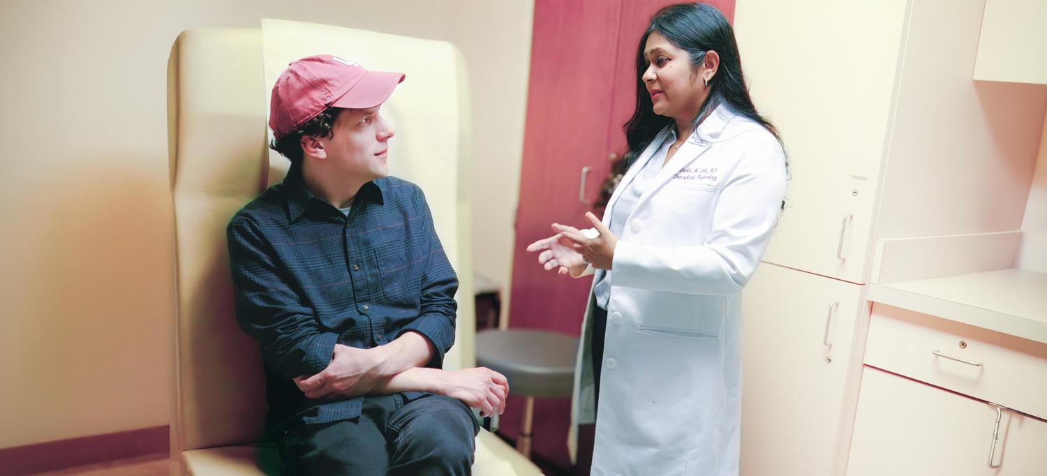 Eisenberg sits in a hospital room talking to Dr. Ali.