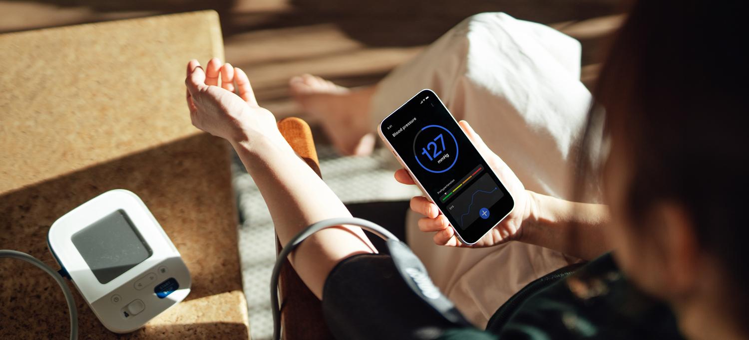 Woman checking her blood pressure and seeing results on her phone.