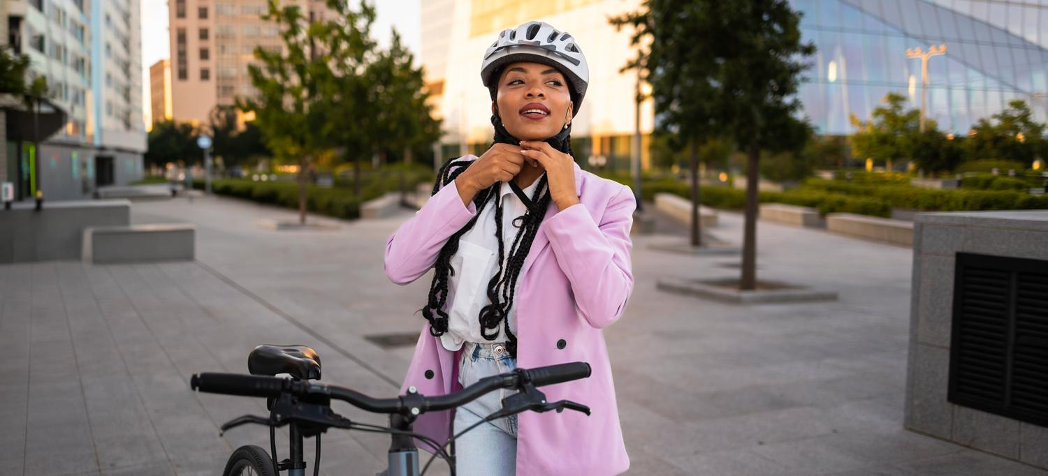 Woman fastens her helmet before riding a bicycle in the city