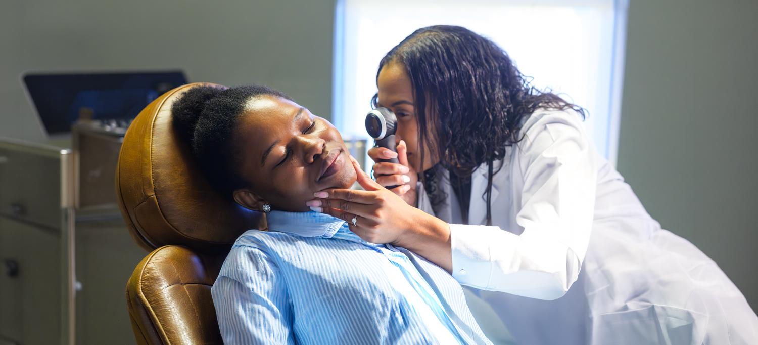 A doctor examines a patient in a chair. 