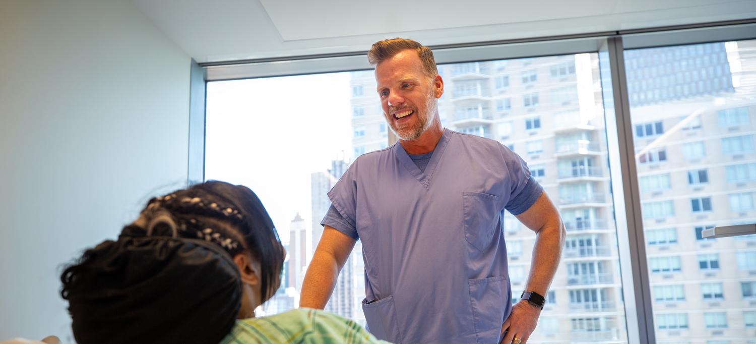 Moore talks to a patient in a hospital bed.