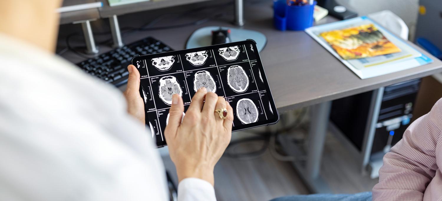 Doctor discussing brain X-rays on a digital tablet with patient 