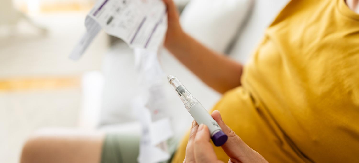 Person holding GLP-1 injection pen reviews instruction sheet.