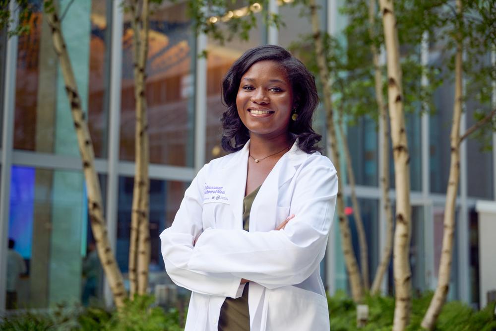 Ogbejesi stands smiling in a courtyard.