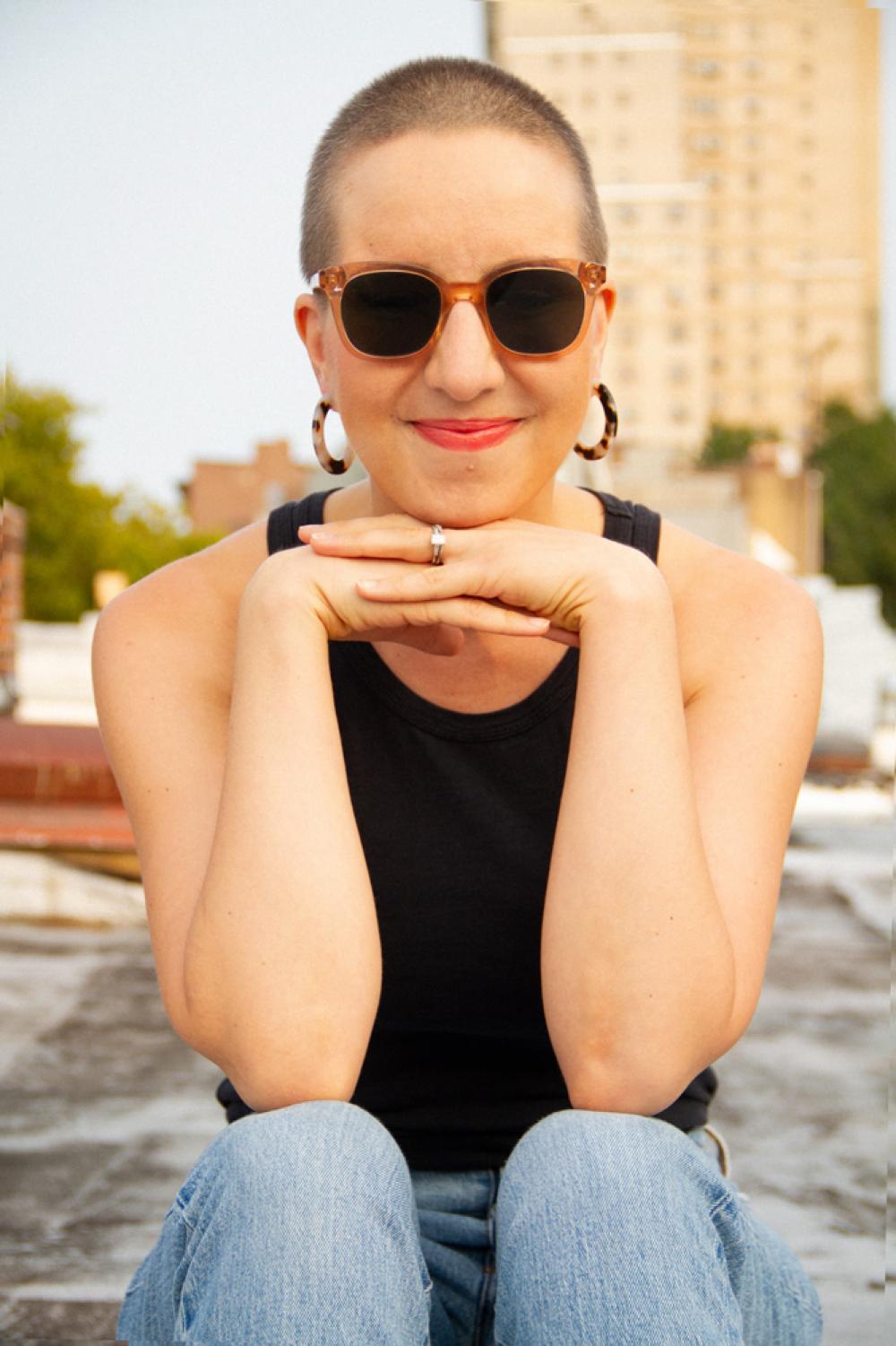 Dorr Drake sits outside, smiling, wearing sunglasses, and has closely cropped hair.