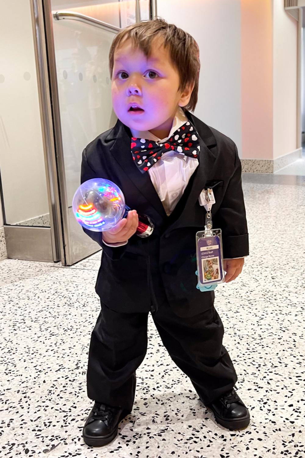 Boy in a tuxedo prepares to join a hospital parade before going home.
