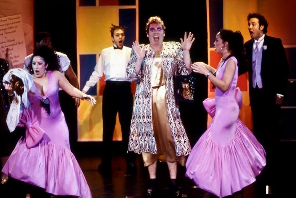 Moore and other actors singing on stage in elaborate costumes. 