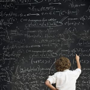 Person Writing on Chalkboard with Complex Math Formulas