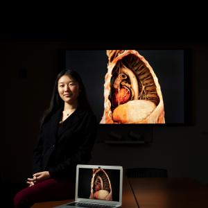 Lily Ge Next to Plastinated Anatomical Model of the Heart, Pulmonary Artery, and Diaphragm Behind the Left Lung