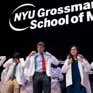 New medical students being helped into their white coats during the ceremony.