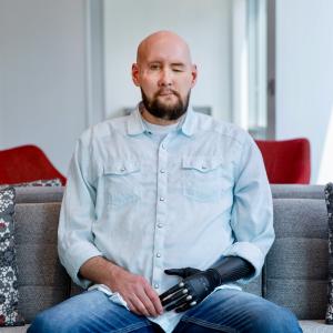 James sitting on a couch, with one eye closed.