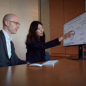 Dr. Oermann and Dr. He look at a drawing of the brain on a monitor. 
