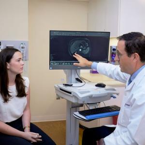 Dr. Augusto Villanueva Rodriguez reviews a scan with a patient.