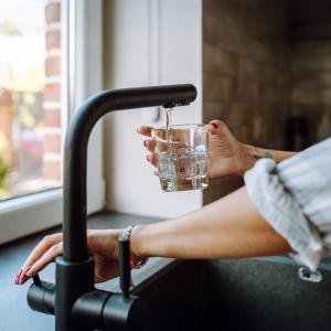 A woman fills a glass of water from a tap