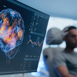 Brain waves on a screen and a man in a chair. 