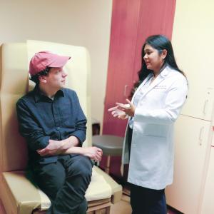 Jesse Eisenburg sits in a hospital room talking to transplant surgeon Nicole M. Ali, MD.