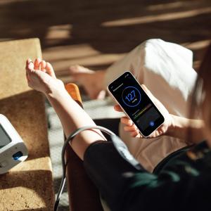 Woman checking her blood pressure and seeing results on her phone.