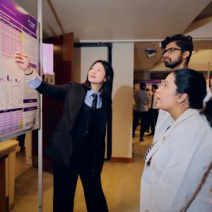 One researcher points to a wall chart while two others look on.