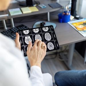 Doctor discussing brain X-rays on a digital tablet with patient 