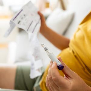 Person holding GLP-1 injection pen reviews instruction sheet.