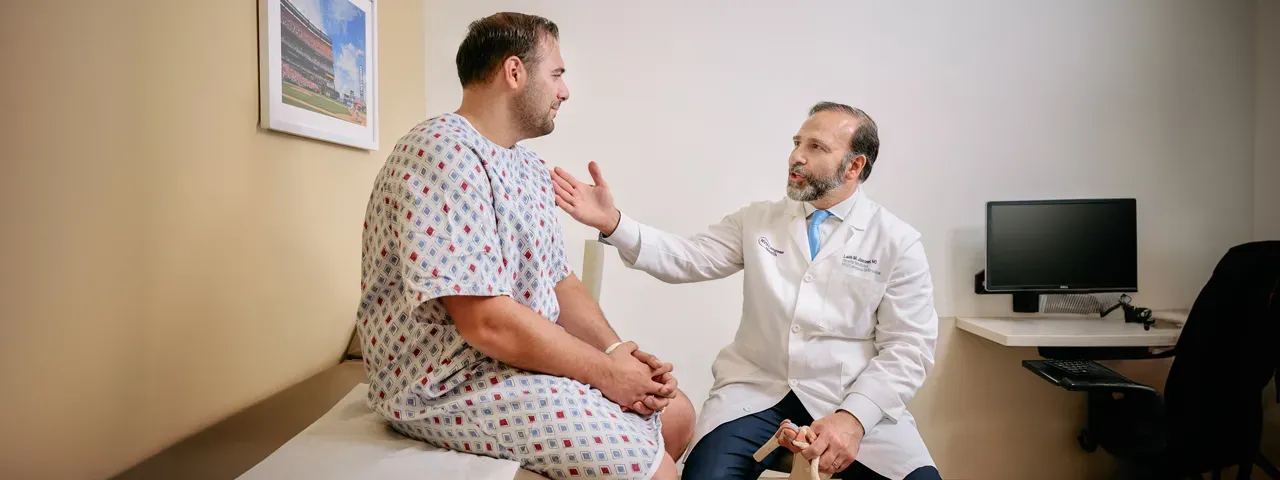 A doctor talks to a patient in a hospital gown.