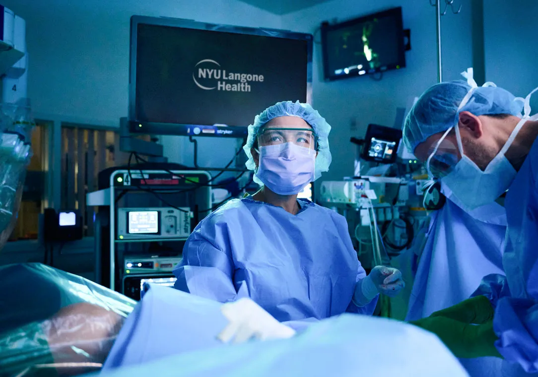 Dr. Kathy Huang and another provider perform a medical procedure in an operating room with advanced equipment.