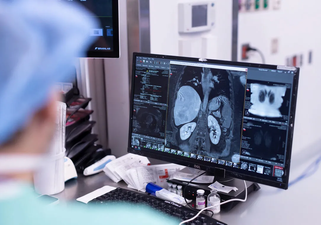 Over-the-shoulder image of a medical professional viewing an imaging report on a desktop computer.