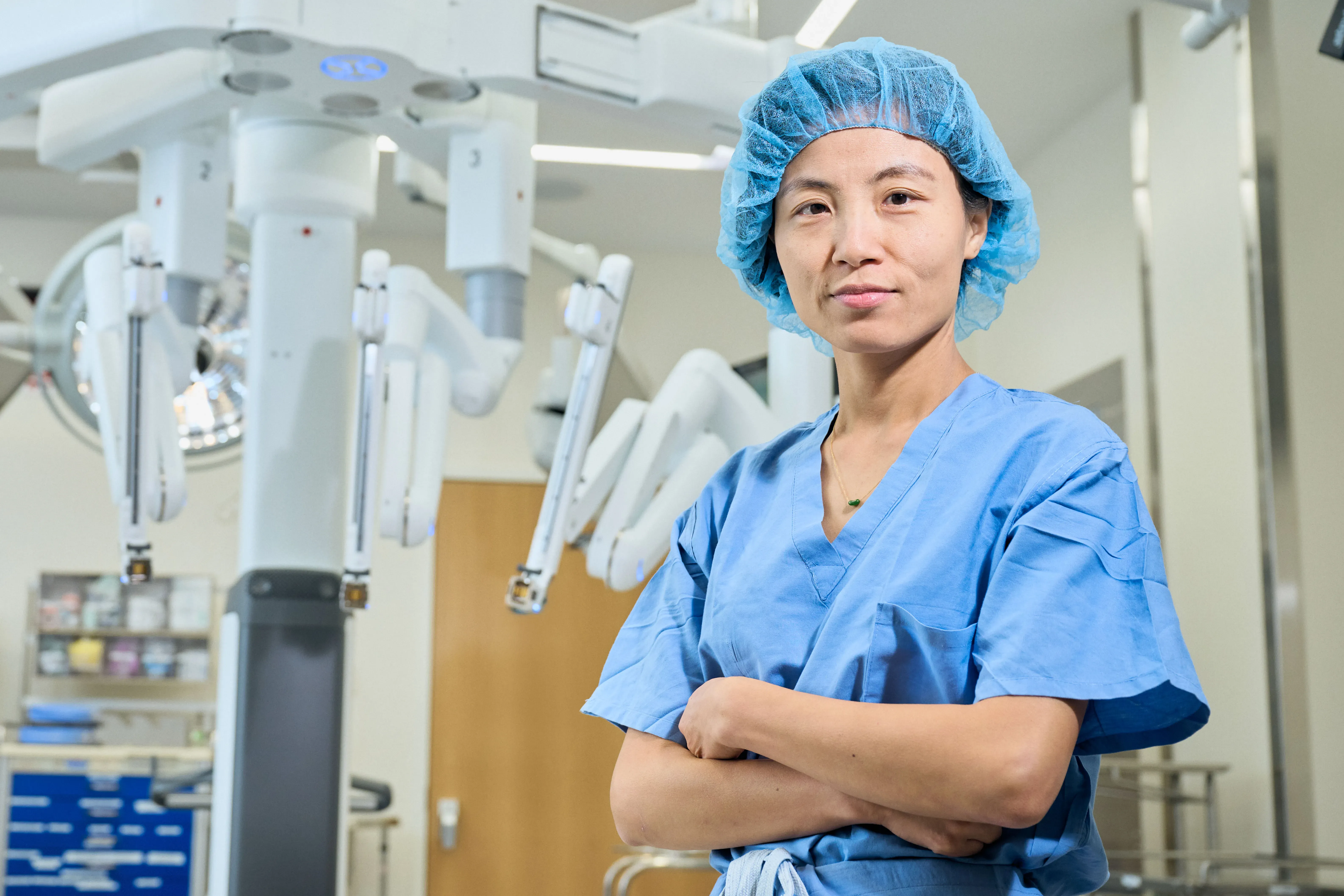 Dr. Kathy Huang stands in an operating room full of advanced surgical equipment. 
