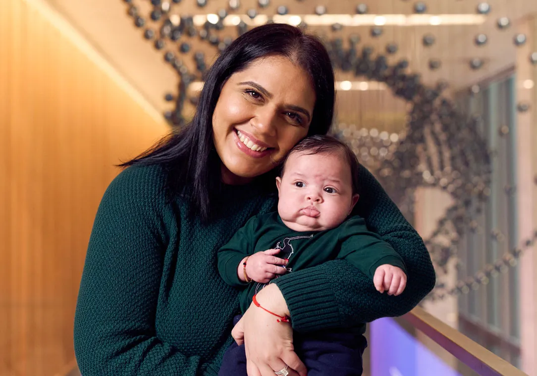 A smiling mother holds her baby. 