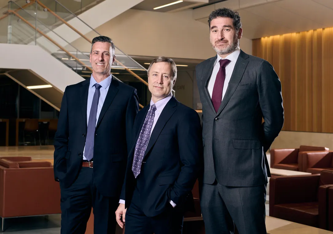 Dr. Patrick G. Northup, Dr. Adam Griesemer, and Dr. Karim J Halazun stand smiling in a nondescript lobby. 