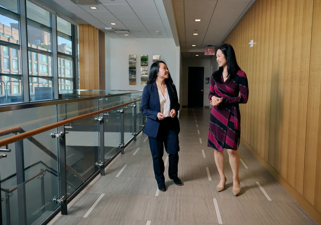 Dr. Jun Levine and Dr. Christine Chung walk and talk in a hallway. 