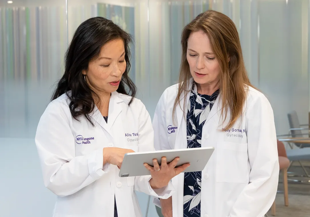 Dr. Alice Tsai and nurse practitioner Holly Gorman stand together while looking at an electronic tablet.