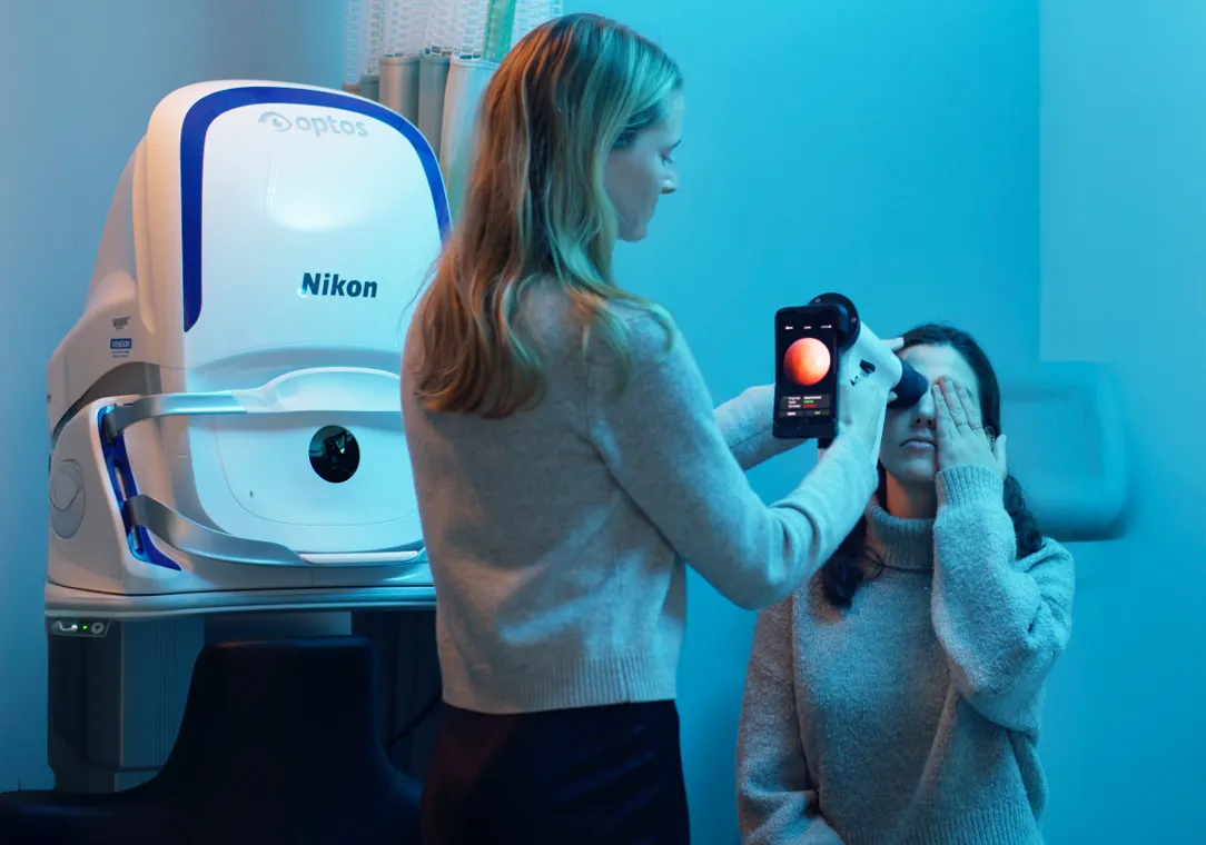A health care provider uses a retina scanner to examine a patient in a medical office.