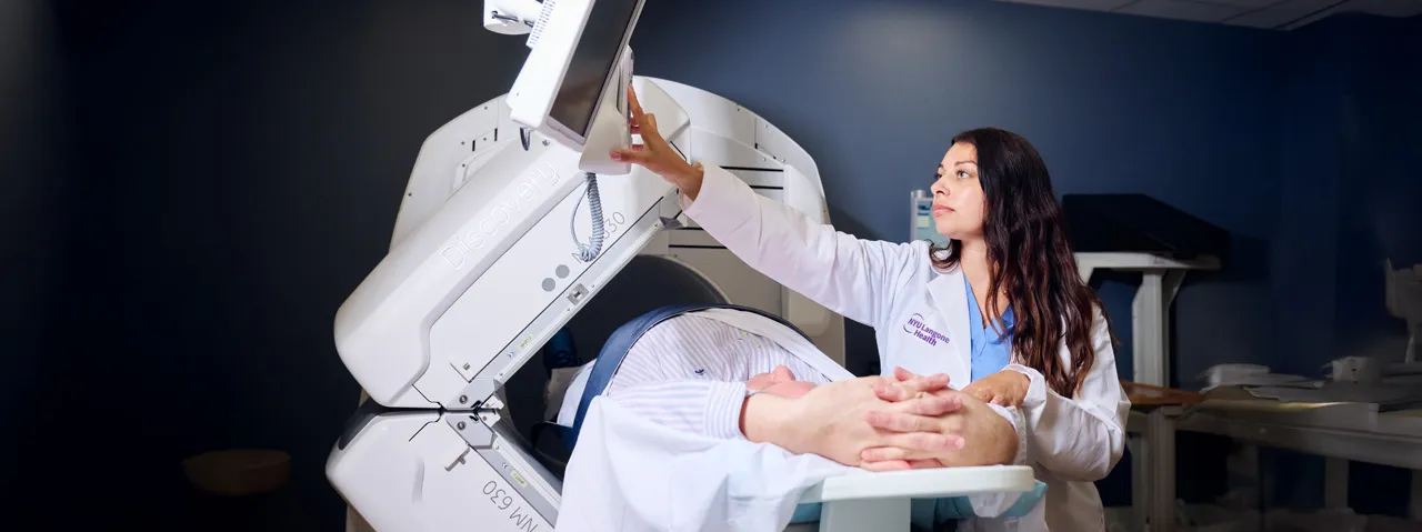 An NYU Langone healthcare provider adjusts the controls of a medical imaging machine in a clinical setting.